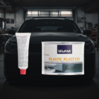 Arrière-plan avec pare-chocs en plastique - PredaColor Black car in a workshop with large plastic repair cans attached to the front, labeled SEICAR Plastic Plast 515 and a tube of adhesive visible on the left side.