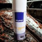 2fa38e05-1800-4cee-95e9-a642bcee96c8 - PredaColor Close-up of a white spray can labeled Wax Protec 472 in a rusted junkyard setting.