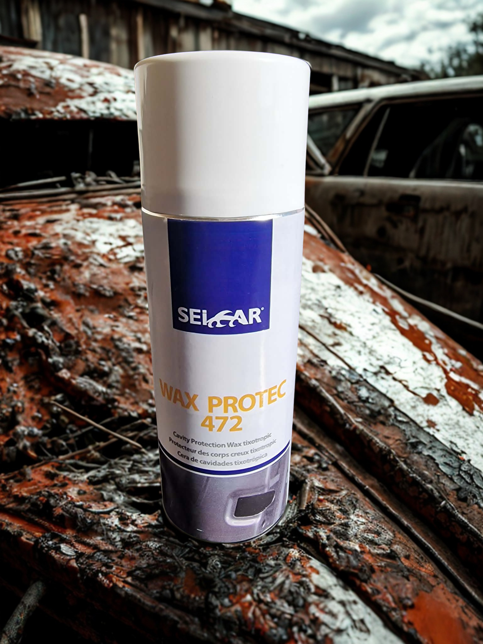 2fa38e05-1800-4cee-95e9-a642bcee96c8 - PredaColor Close-up of a white spray can labeled Wax Protec 472 in a rusted junkyard setting.