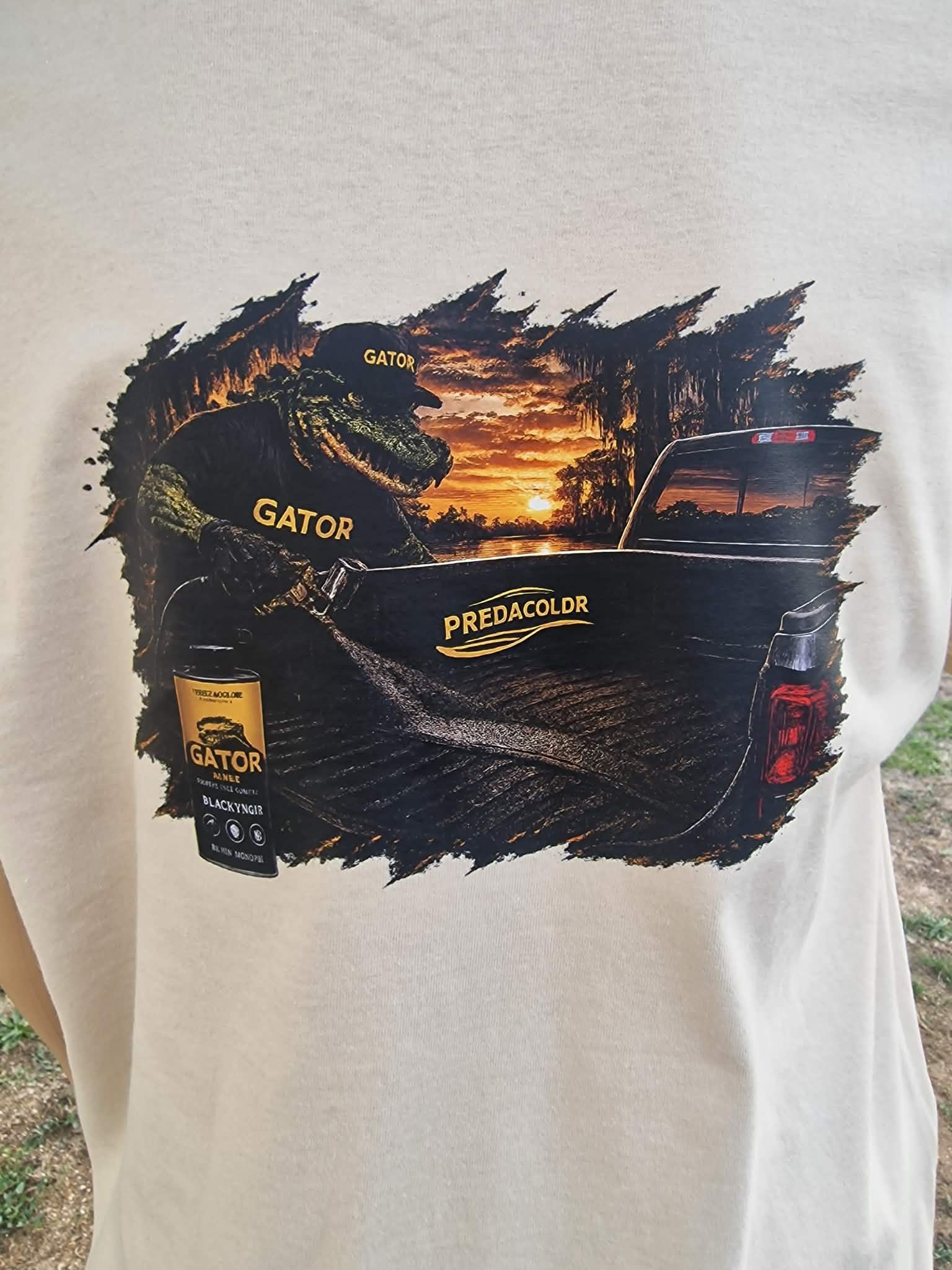 3 1 DOS - PredaColor Graphic on a white T-shirt: an alligator figure with the word GATOR on its hat and clothing, beside a pickup truck at sunset.