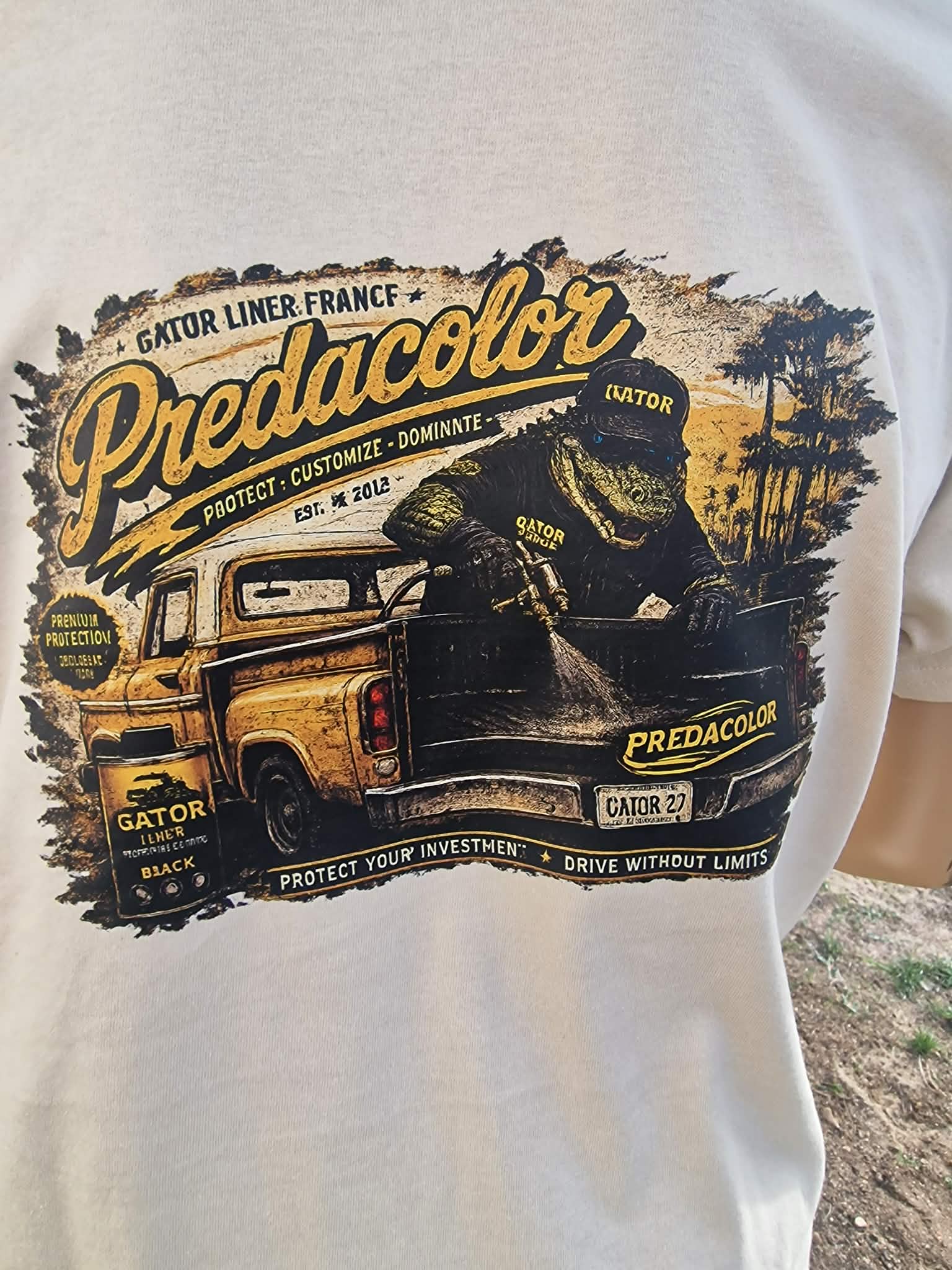 4 2 - PredaColor White T-shirt featuring a vintage-style graphic: a yellow and black pickup with a dinosaur rider and bold 'Predicolor' text across the top, palm trees in the background.