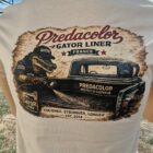 Back view of a beige T-shirt with a vintage Predacolor Gator Liner France graphic featuring a gator and a truck